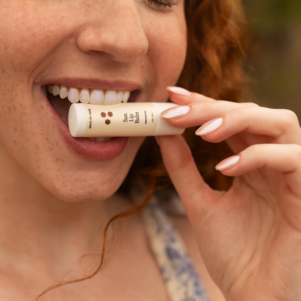 Woman biting lip balm stick between her teeth with a slightly blurred background