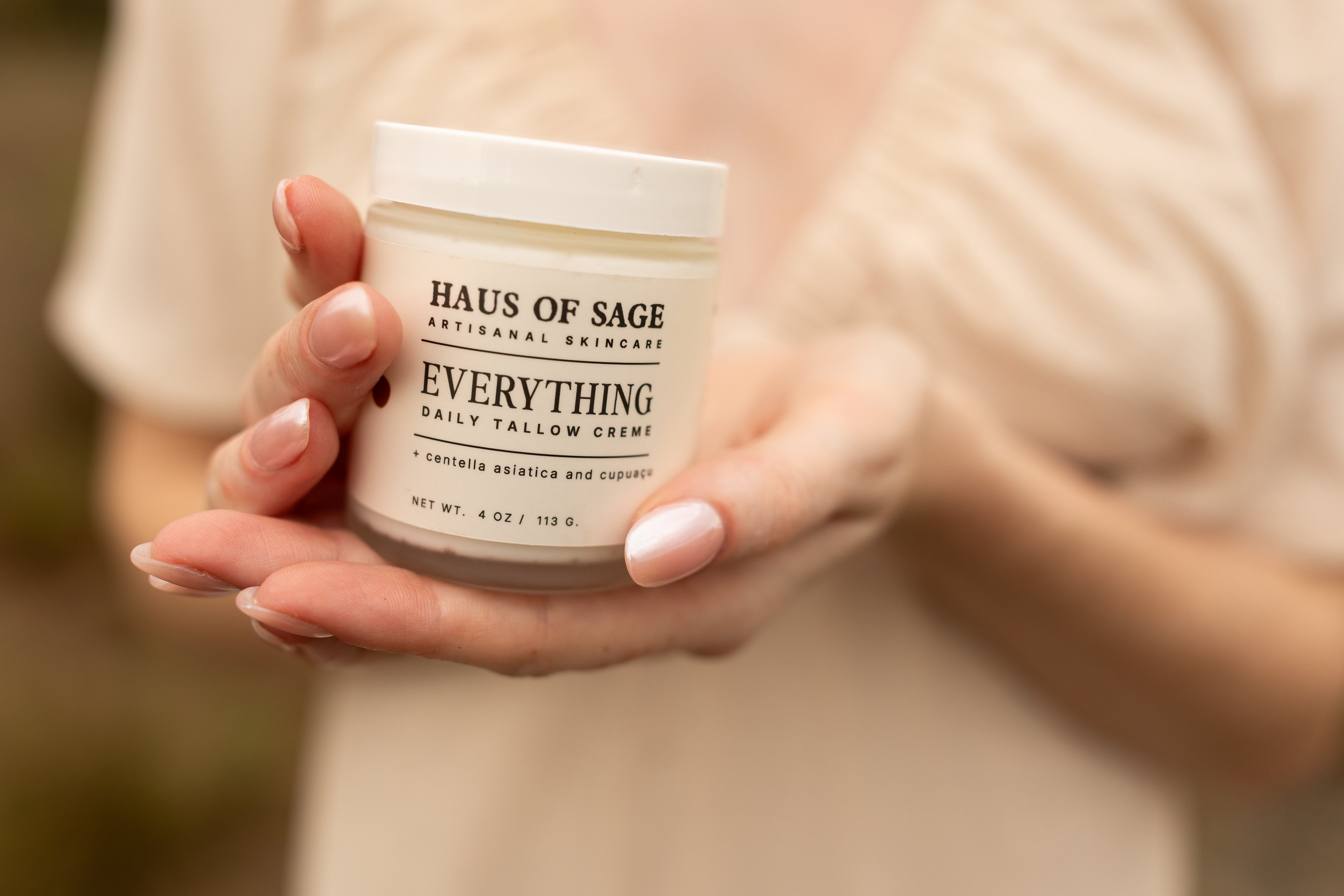 Hands holding  jar of 'Haus of Sage Everything Daily Tallow Creme' .