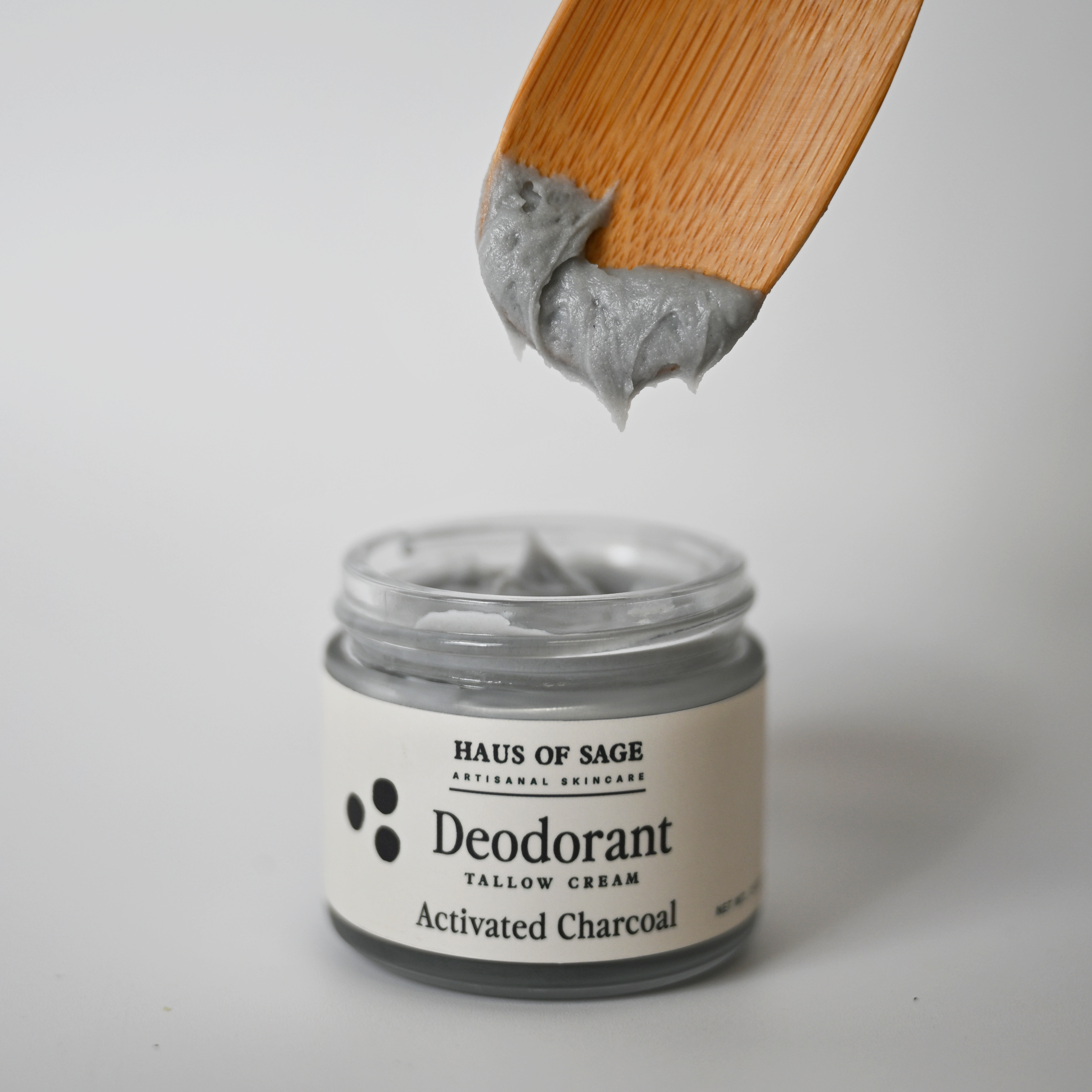 Jar of Haus of Sage deodorant with a wooden applicator on a light gray background