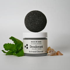 Deodorant jar with activated charcoal ball and ginger root on a white background