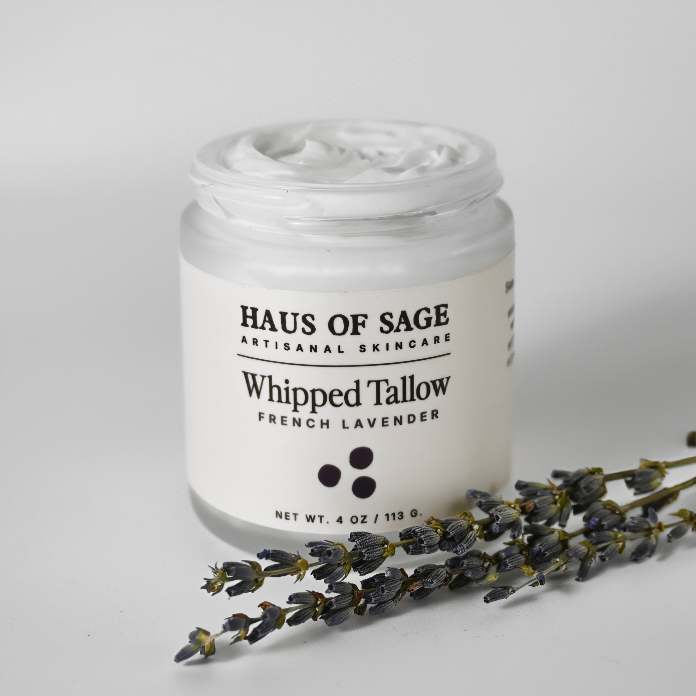 Jar of Haus of Sage Whipped Tallow with lavender flowers on a gray background