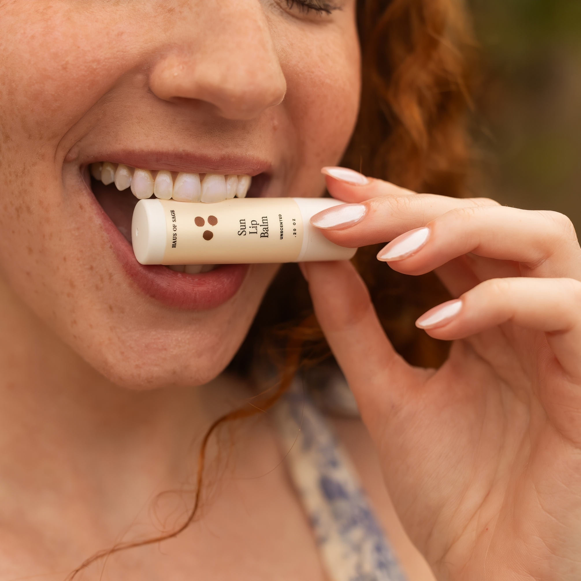 Woman biting lip balm stick between her teeth with a slightly blurred background